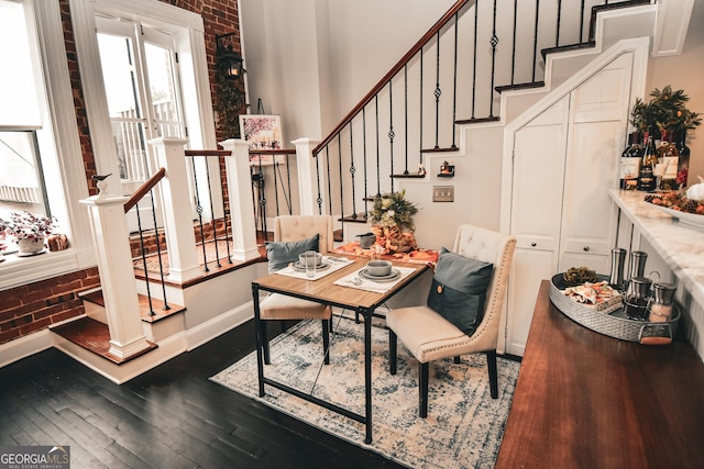 dining room featuring dark hardwood / wood-style floors and brick wall