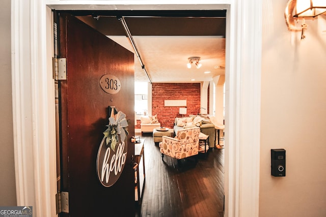 hallway with brick wall and hardwood / wood-style floors