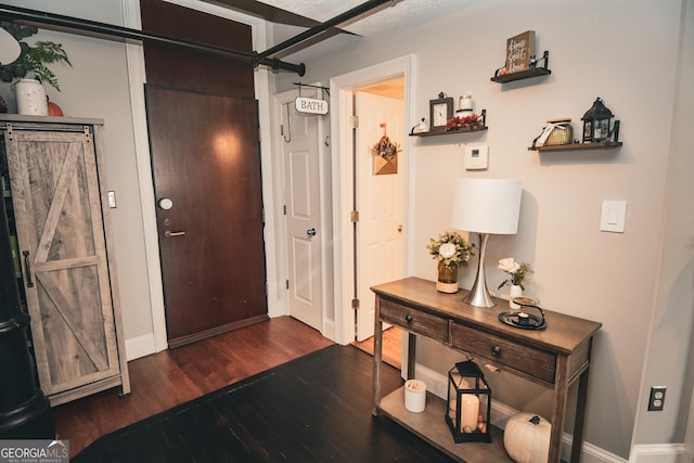 foyer entrance featuring a barn door and dark hardwood / wood-style floors