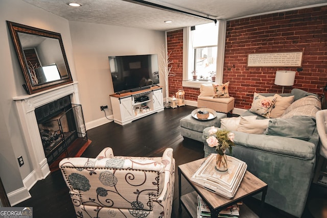 living room featuring a textured ceiling, dark hardwood / wood-style floors, and brick wall