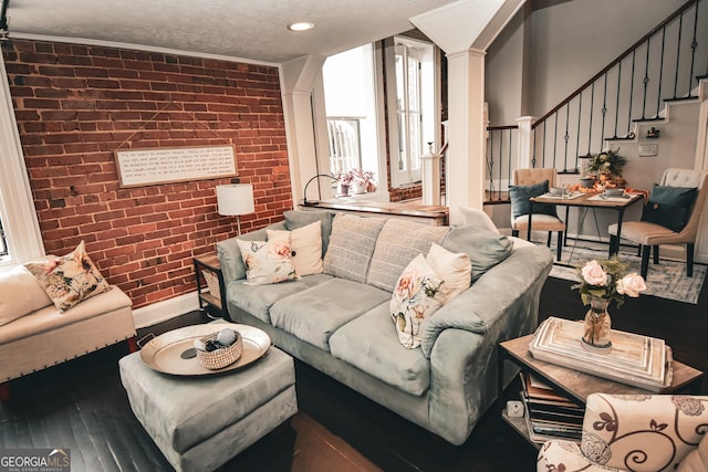 living room featuring brick wall, a textured ceiling, ornamental molding, and hardwood / wood-style floors