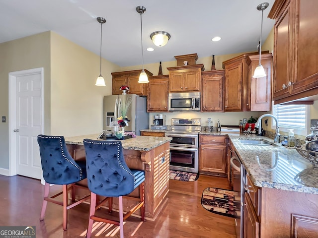 kitchen featuring a breakfast bar area, stainless steel appliances, a sink, and decorative light fixtures