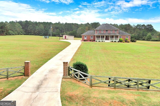 view of front of home with covered porch, a front yard, and a storage unit