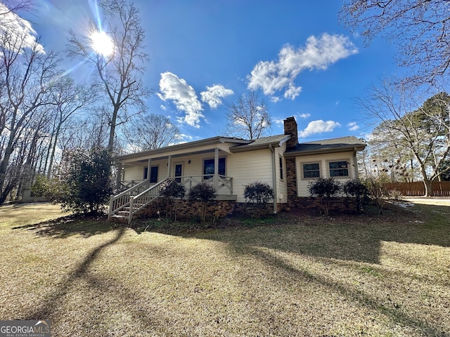 ranch-style home featuring covered porch and a front lawn