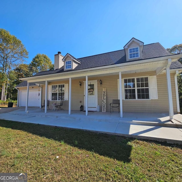 view of front of house featuring a porch, a front yard, and a garage