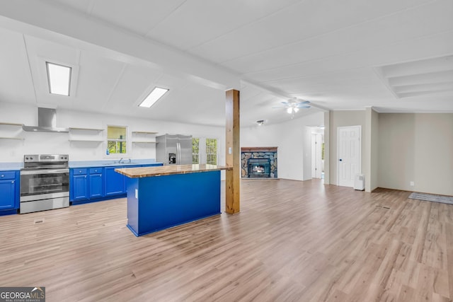 kitchen with ceiling fan, appliances with stainless steel finishes, blue cabinetry, light hardwood / wood-style flooring, and lofted ceiling with beams