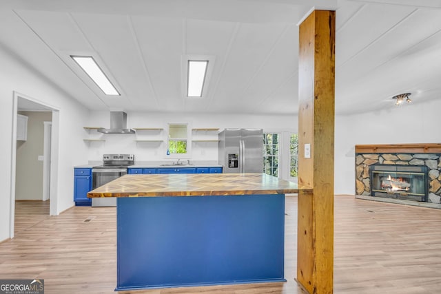 kitchen featuring butcher block counters, blue cabinetry, stainless steel appliances, and light hardwood / wood-style flooring