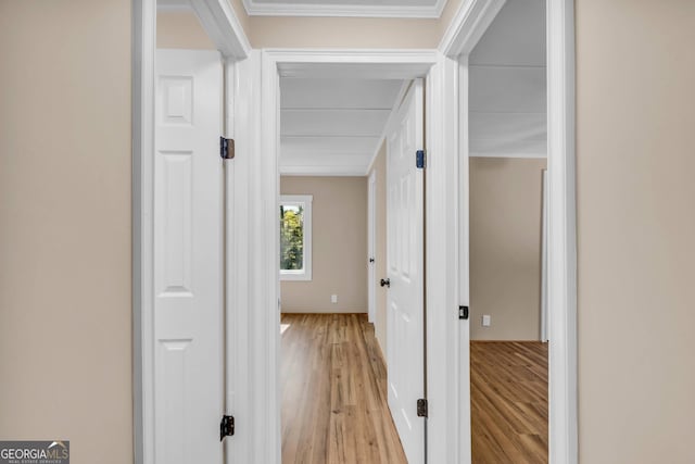 hallway with ornamental molding and light hardwood / wood-style flooring