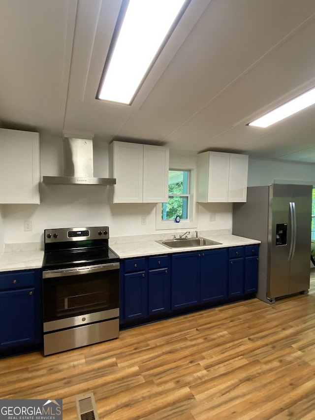 kitchen featuring sink, stainless steel appliances, wall chimney exhaust hood, white cabinets, and blue cabinetry