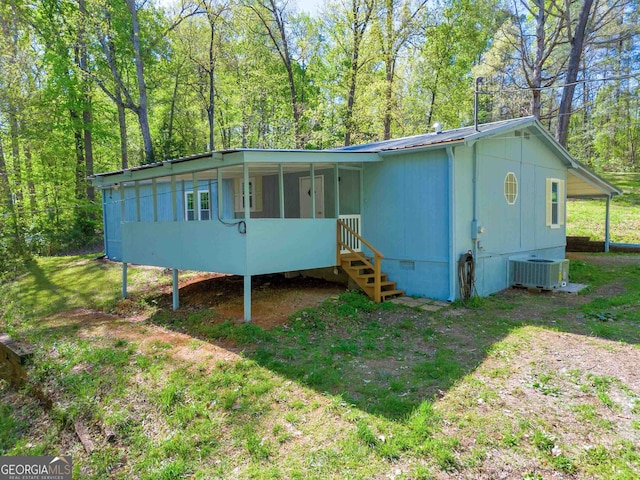 rear view of house featuring cooling unit, a lawn, and a sunroom