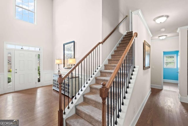 entrance foyer featuring dark hardwood / wood-style flooring, crown molding, plenty of natural light, and a towering ceiling