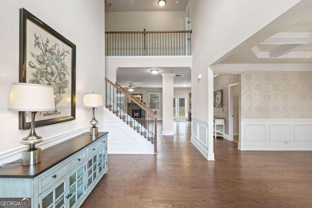 entryway with a high ceiling, ornamental molding, ceiling fan, and dark wood-type flooring