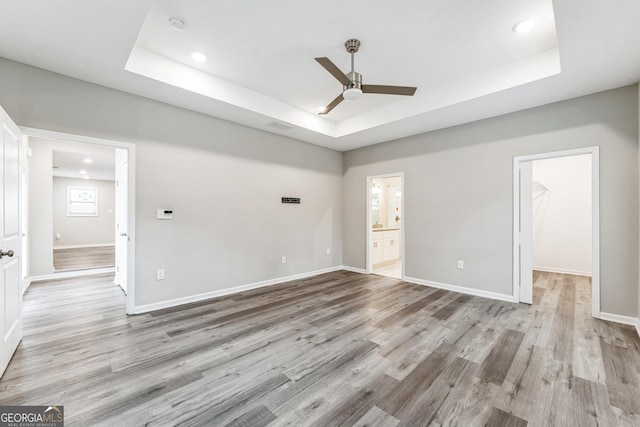 unfurnished room featuring light hardwood / wood-style floors, a raised ceiling, and ceiling fan