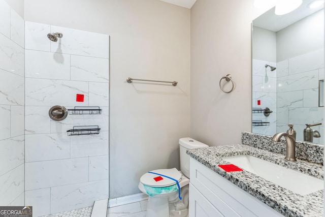 bathroom with vanity, toilet, and tiled shower