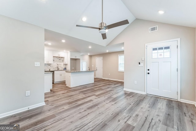 interior space with ceiling fan, light hardwood / wood-style flooring, vaulted ceiling, and sink