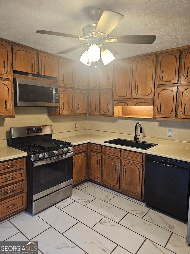 kitchen featuring appliances with stainless steel finishes, a textured ceiling, sink, and ceiling fan