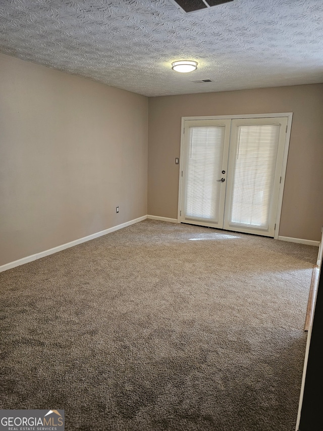 empty room with french doors, carpet flooring, and a textured ceiling