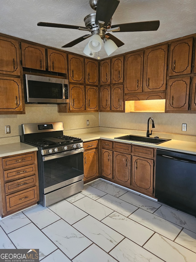 kitchen featuring sink, appliances with stainless steel finishes, a textured ceiling, and ceiling fan