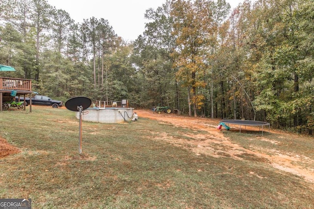 view of yard with a trampoline and a swimming pool side deck