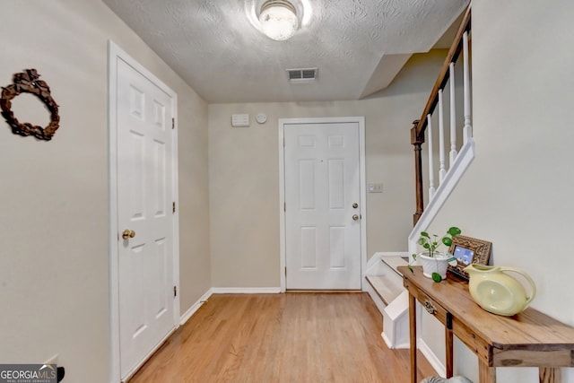 foyer entrance with light hardwood / wood-style floors and a textured ceiling