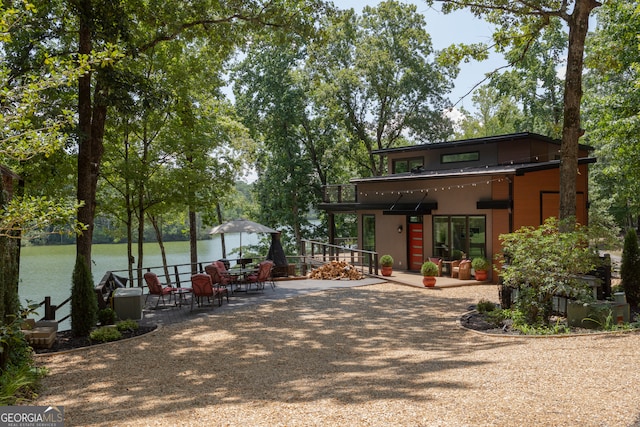 back of house featuring a water view and a patio area