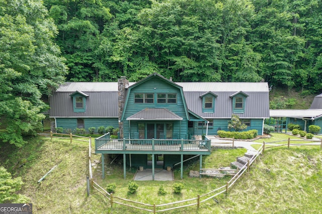 rear view of property featuring a wooden deck and a lawn