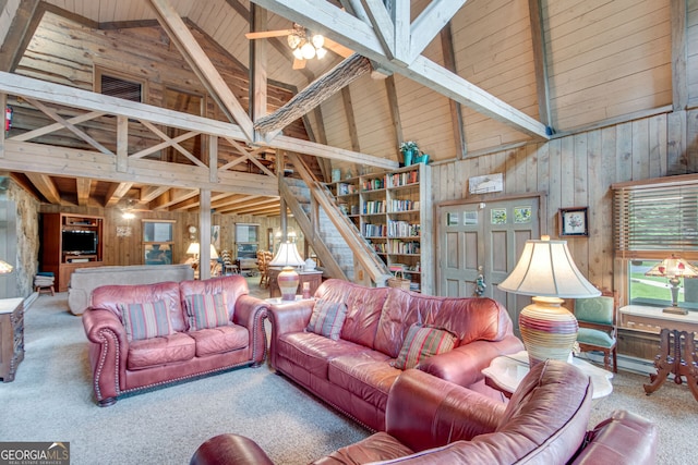 living room with high vaulted ceiling, wooden walls, carpet flooring, and beam ceiling