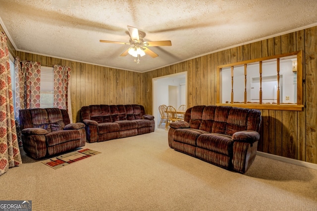 carpeted living room featuring a textured ceiling, wooden walls, and ceiling fan