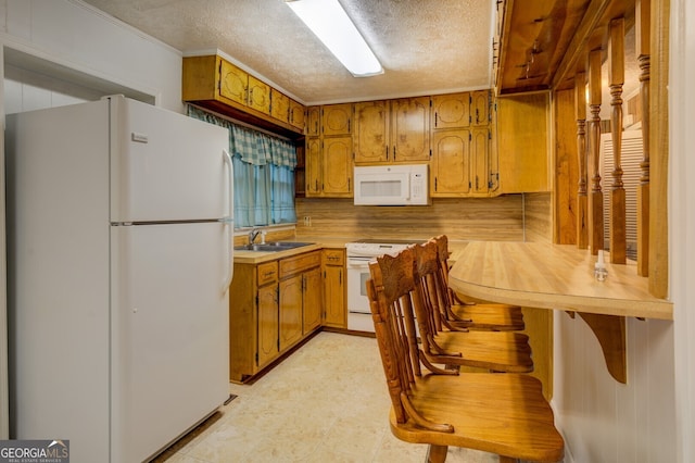 kitchen with a textured ceiling, sink, and white appliances