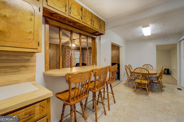 bar featuring ceiling fan, a textured ceiling, and crown molding