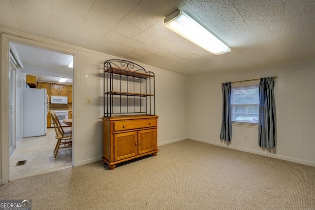 unfurnished room with wood walls, light carpet, and crown molding