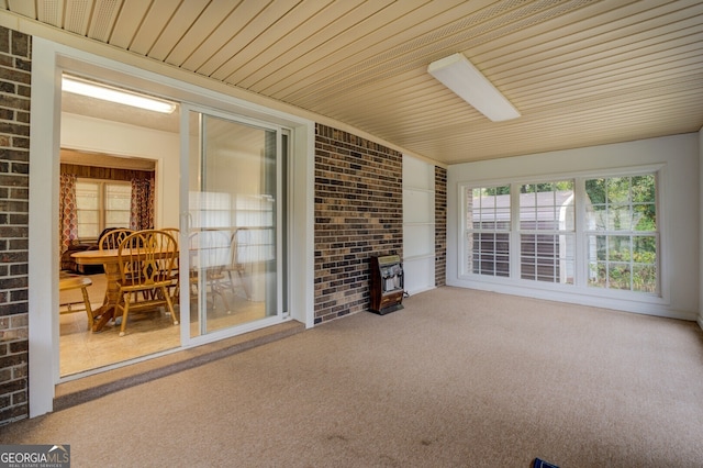 interior space with wooden ceiling, brick wall, carpet flooring, and a wood stove