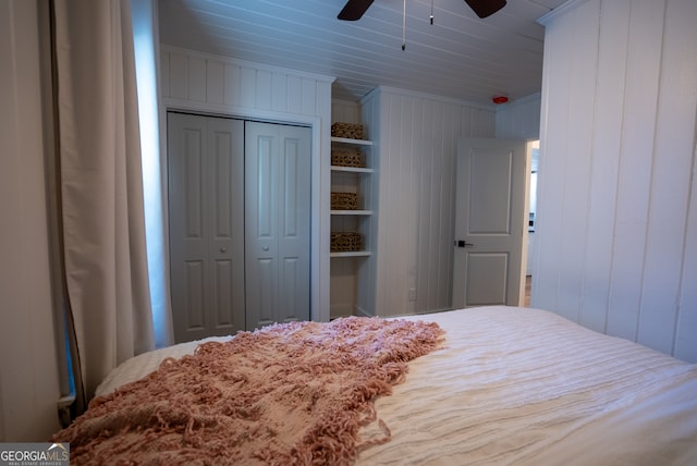 bedroom with ornamental molding, wood walls, ceiling fan, and a closet