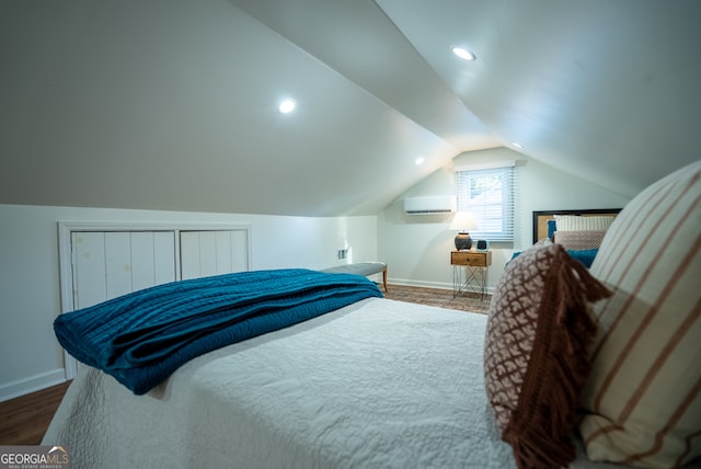 bedroom with dark wood-type flooring, lofted ceiling, and a wall unit AC