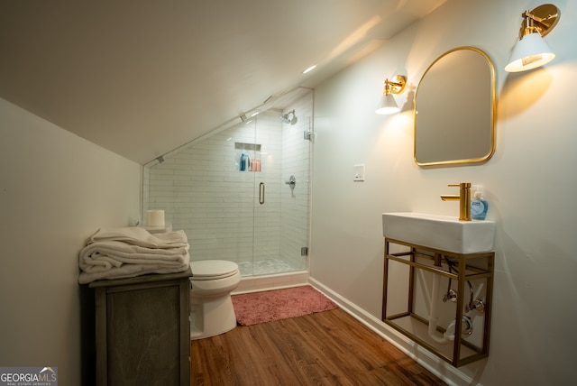 bathroom featuring hardwood / wood-style floors, toilet, vaulted ceiling, and a shower with shower door