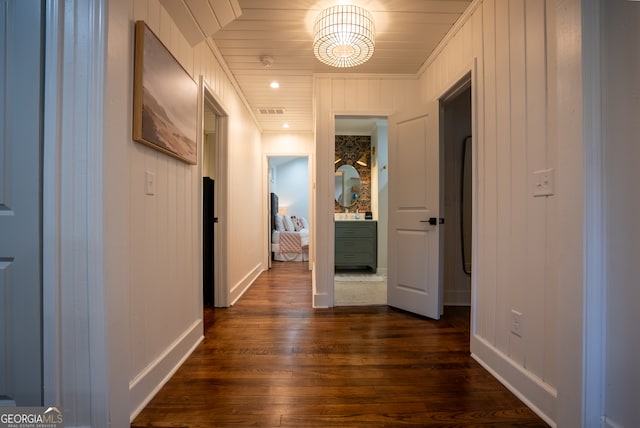 hallway featuring dark wood-type flooring and wood walls