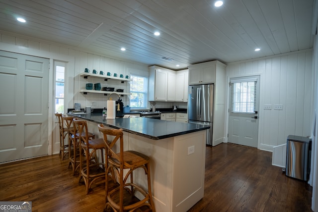 kitchen with stainless steel fridge, white cabinetry, a kitchen bar, dark hardwood / wood-style flooring, and kitchen peninsula