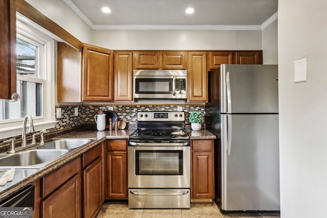 kitchen featuring tasteful backsplash, ornamental molding, stainless steel appliances, sink, and dark stone countertops