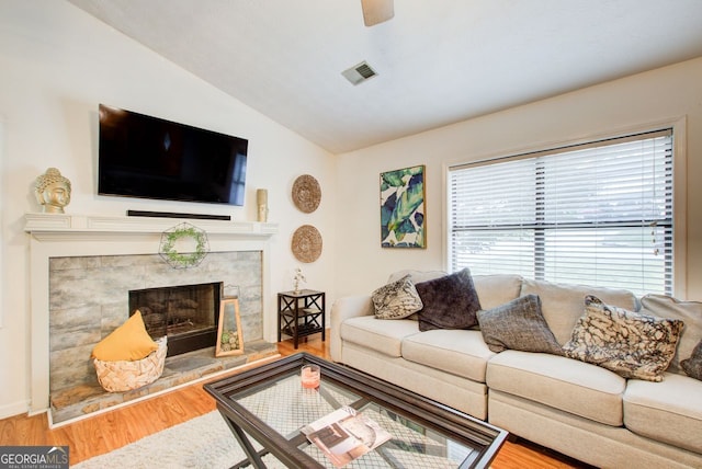 living room with wood-type flooring, vaulted ceiling, and a fireplace