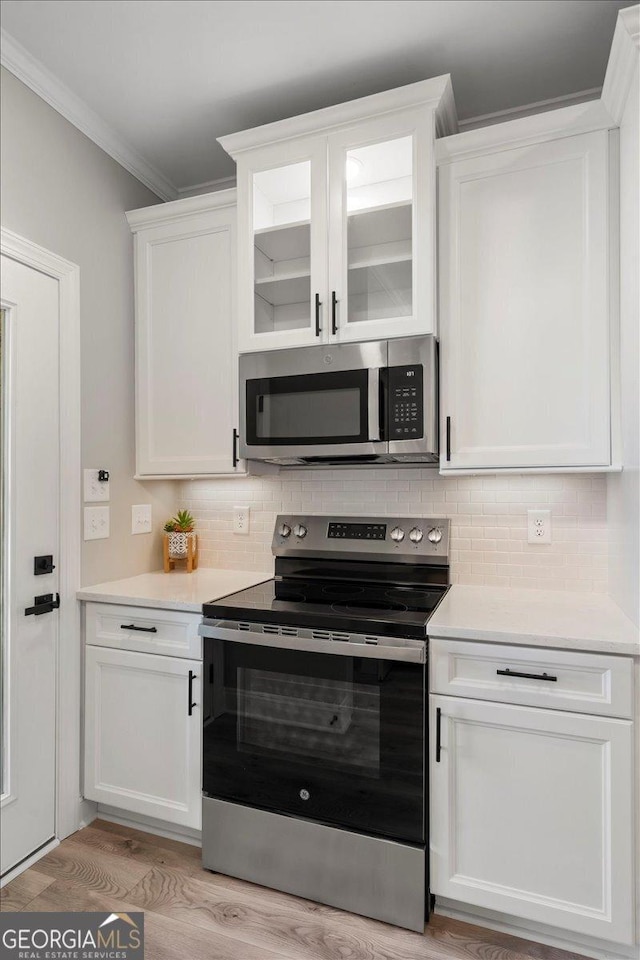 319 S Madison Ave, Monroe, GA 30655 - kitchen featuring stainless steel appliances, white cabinetry, light countertops, ornamental molding, and tasteful backsplash