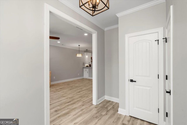 hallway with ornamental molding, light hardwood / wood-style floors, and a notable chandelier