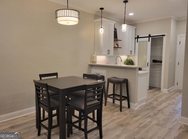 319 S Madison Ave, Monroe, GA 30655 - dining room with ornamental molding, light wood finished floors, baseboards, recessed lighting, and a barn door