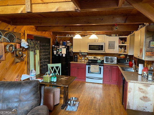 kitchen featuring black appliances, wood walls, light hardwood / wood-style floors, and beam ceiling