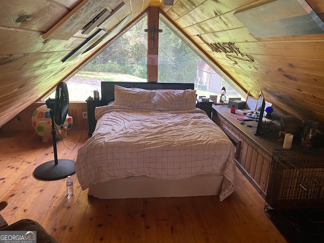 bedroom featuring hardwood / wood-style flooring, wooden walls, and lofted ceiling