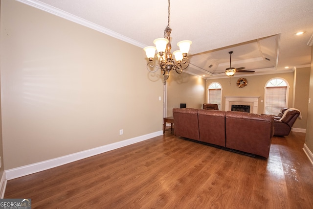 living room with ceiling fan with notable chandelier, wood-type flooring, crown molding, and a tray ceiling