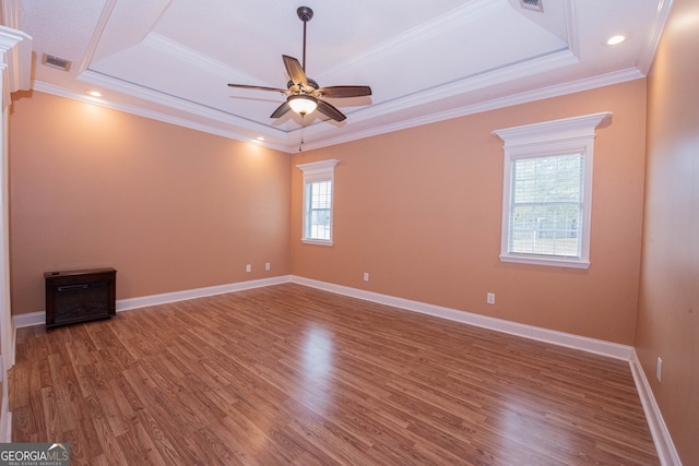 empty room featuring ornamental molding, hardwood / wood-style floors, and a raised ceiling