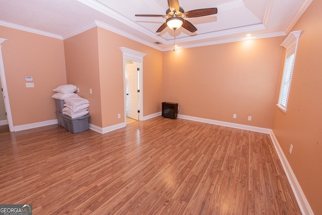 spare room featuring a tray ceiling, hardwood / wood-style flooring, ceiling fan, and crown molding