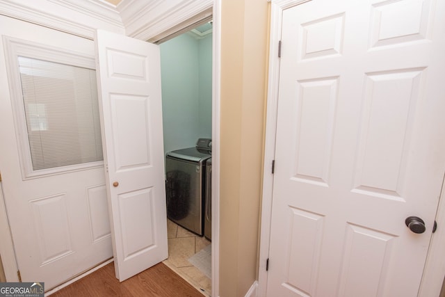 clothes washing area with hardwood / wood-style floors, ornamental molding, and washer / dryer