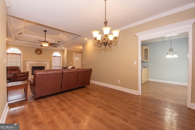 living room featuring a tray ceiling, hardwood / wood-style floors, ceiling fan with notable chandelier, and crown molding