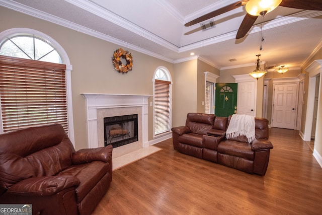 living room with ceiling fan, hardwood / wood-style flooring, ornamental molding, and a fireplace